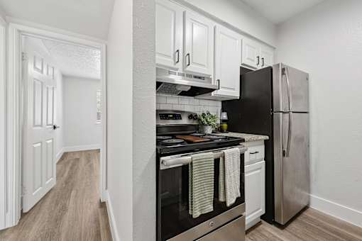 A kitchen with black appliances and white cabinets.