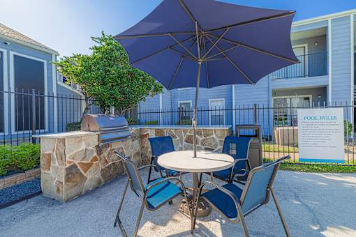 A patio with a table, chairs and an umbrella.