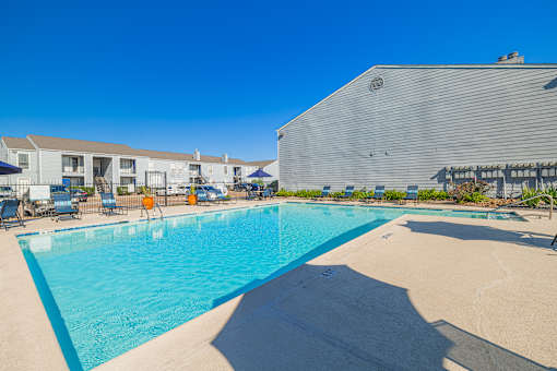 A large swimming pool with a blue tinted water and a white building in the background.