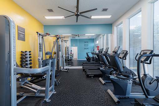 A gym with a variety of equipment including treadmills, stationary bikes, and weight machines.