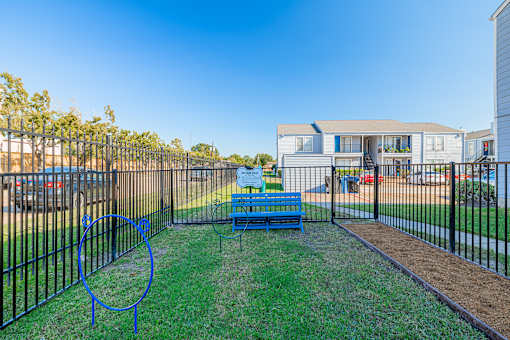 A playground with a blue swing set and a metal fence.