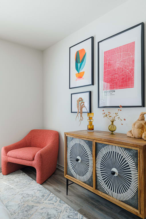 a living room with a cabinet and a chair and pictures on the wall