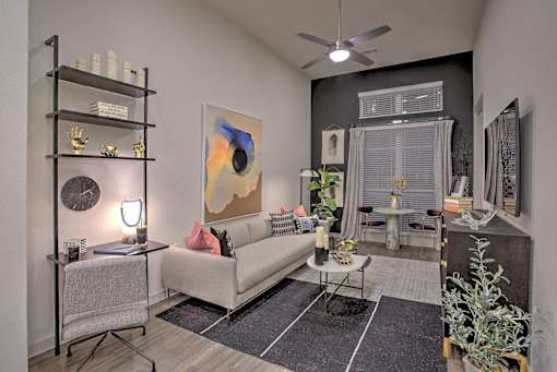A living room with a white couch, a black shelf, and a painting on the wall.