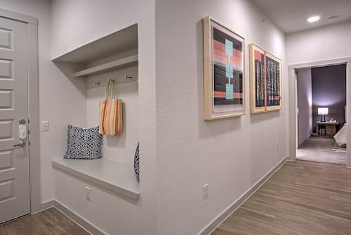 A hallway with a bench and two paintings on the wall.