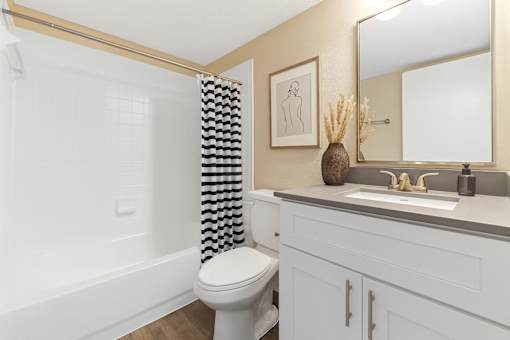A bathroom with a white toilet and a checkered shower curtain.