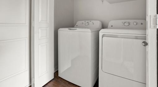 Two white front loading washing machines in a laundry room.