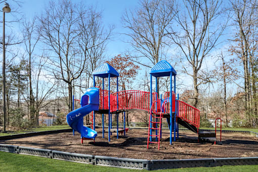 A playground with a red and blue slide and a blue roofed structure.