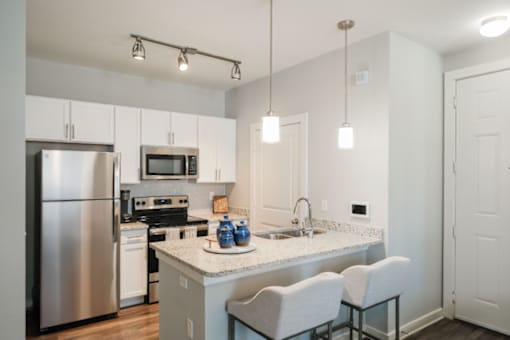A kitchen with a stainless steel refrigerator, microwave, and oven.
