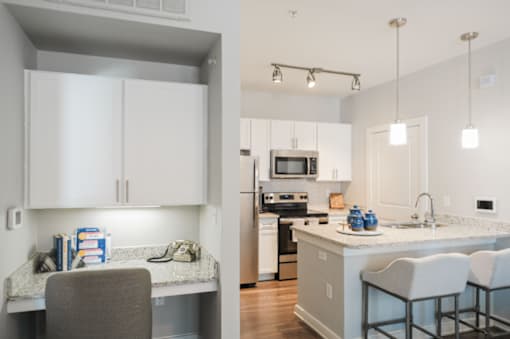 A kitchen with white cabinets and a grey counter.