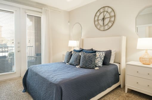 A bedroom with a bed, nightstand, and a clock on the wall.