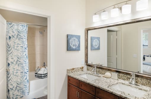 A bathroom with a patterned shower curtain and a large mirror.