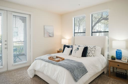A bedroom with a white bed and a tray of food on it.