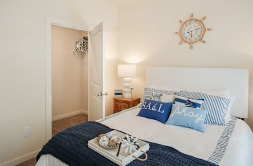 A bedroom with a bed, a clock, and a lamp.