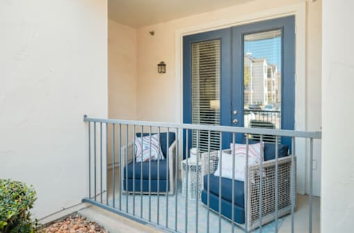 A balcony with a blue chair and a white pillow.