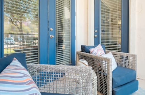 A blue chair with a pillow and a striped cushion is in front of a window.