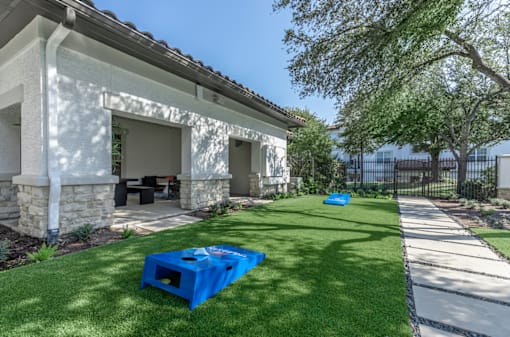 A blue plastic container is placed on a green lawn in front of a house.