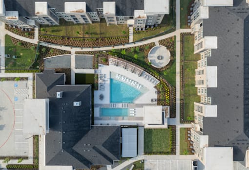 A bird's eye view of a building with a swimming pool in the middle.
