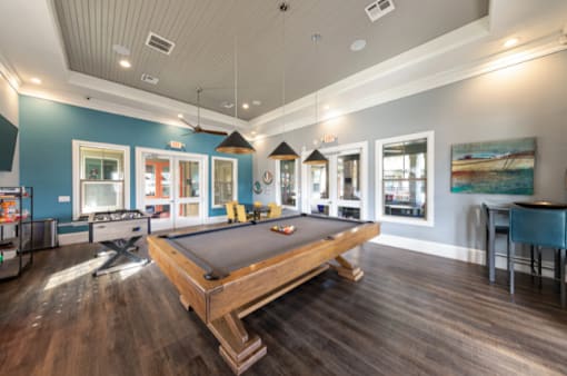 A pool table is in the middle of a room with a blue wall.