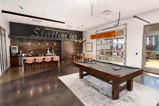 A room with a pool table and a bar area.