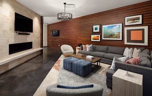 A living room with a grey couch, a blue ottoman, and a fireplace.