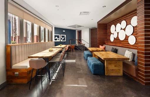 A long wooden table with chairs and a bench is in a room with a brick wall.