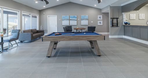 A pool table is in the middle of a room with a couch and a chair.