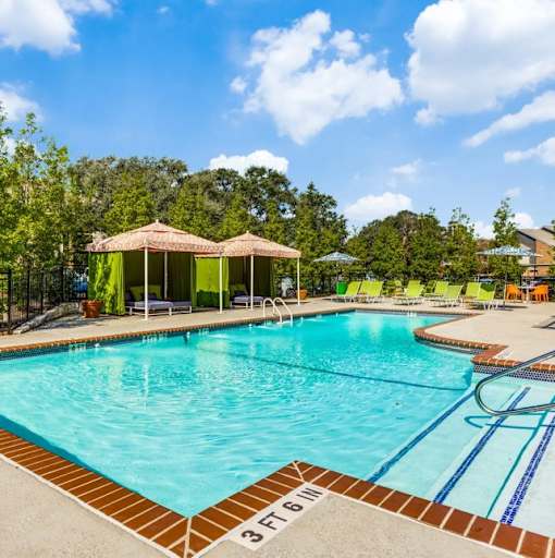 A swimming pool with a pavilion and lounge chairs.