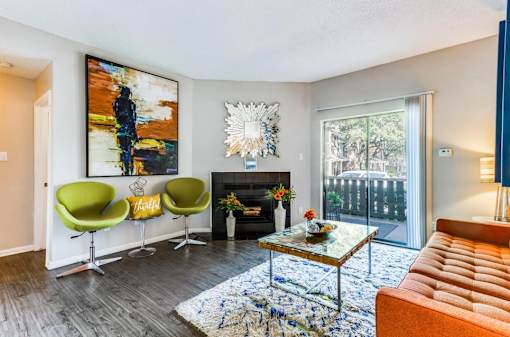 A living room with a fireplace, two chairs, and a painting on the wall.