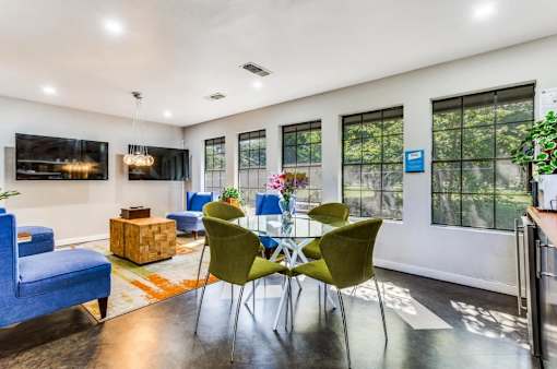 A modern living room with a blue sofa, green chairs, and a wooden coffee table.