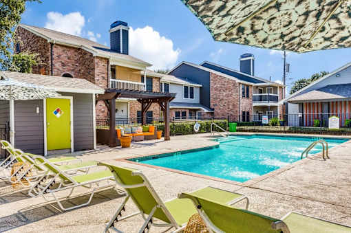 A pool area with sun loungers and a building in the background.
