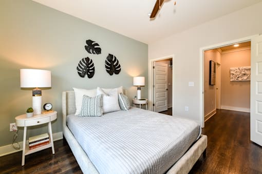 A bedroom with a bed, nightstand, and a plant on the wall.