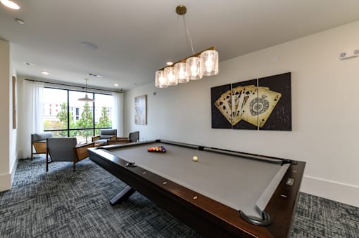 A pool table in a room with a chair and a painting on the wall.