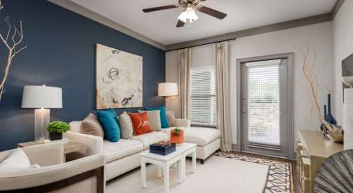 A living room with a white couch, a side table, and a ceiling fan.
