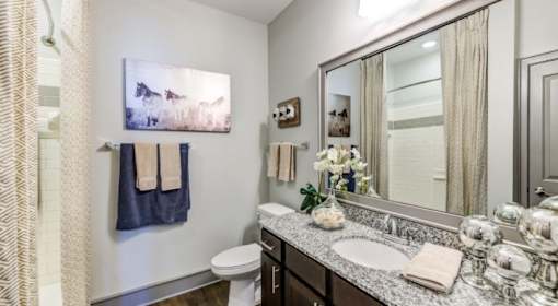 A bathroom with a toilet, sink, and a painting of a horse.