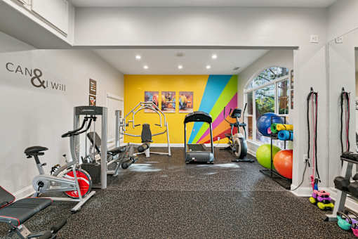 A gym with a variety of equipment including treadmills, weights, and exercise machines.