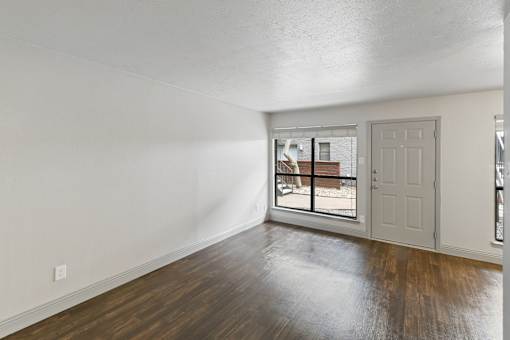A room with a white door and a window with a view of a balcony.