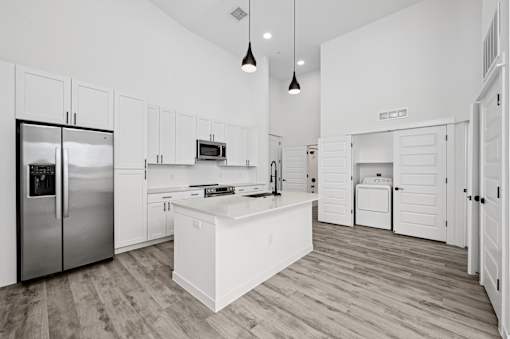 A modern kitchen with a refrigerator, microwave, oven, and cabinets.