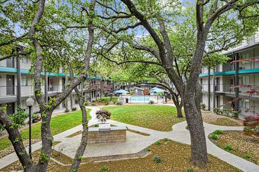A courtyard with a fountain surrounded by trees and buildings.