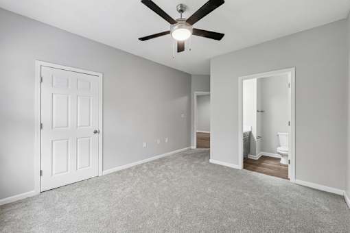 A room with a ceiling fan and carpeted floor.