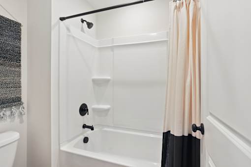 A white bathroom with a black and white bathtub.
