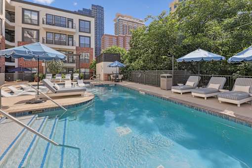 A swimming pool with a metal ladder and sun loungers.