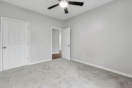A room with a ceiling fan and two doors.