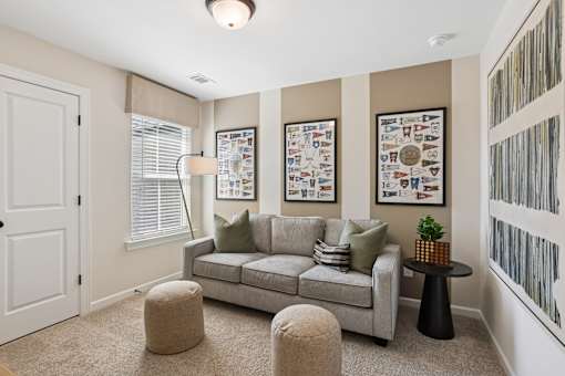A living room with a grey couch, a small table, and a framed picture on the wall.