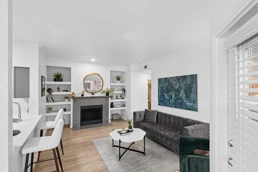 A modern living room with a grey couch and a fireplace.