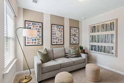 A living room with a grey couch, a floor lamp, and pictures on the wall.