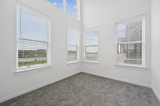 A room with three windows and carpeted floor.