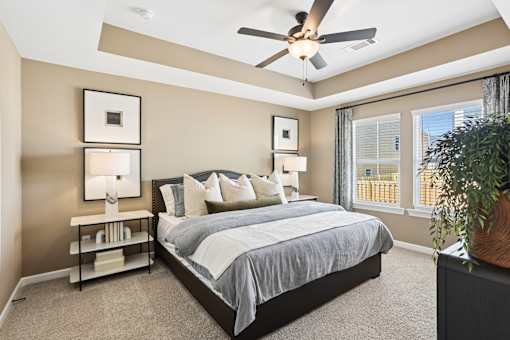 A bedroom with a bed, nightstand, and a ceiling fan.