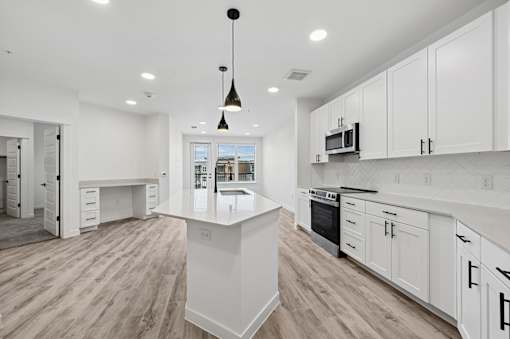 A modern kitchen with white cabinets and a wooden floor.