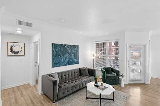 A living room with a grey sofa, a green armchair, and a painting on the wall.