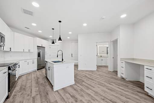 A modern kitchen with white cabinets and a wooden floor.
